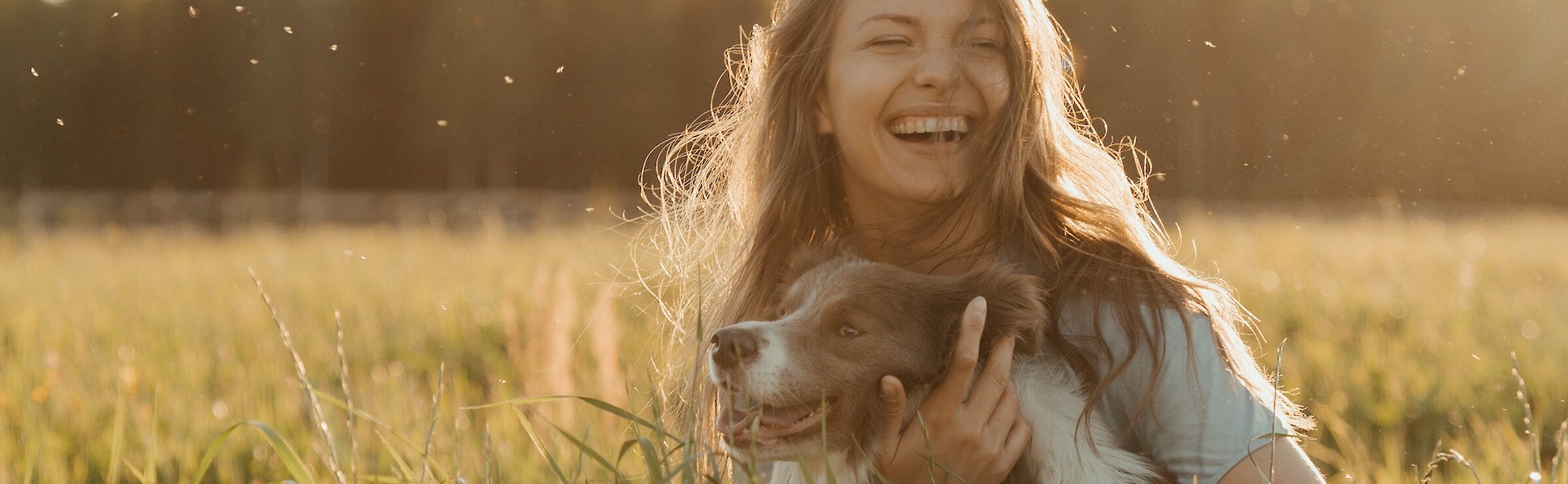 Laughing woman and her dog in a field