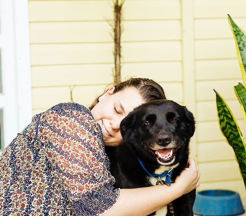 Woman hugging dog outside a house